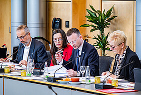 Bezirkstagspräsident Peter Daniel Forster (2.v.r.), Bezirkstagsvizepräsidentin Christa Heckel (2.v.l.), Direktorin der Bezirksverrwaltung Manuela Eppe-Sturm (r.) und Bezirkskämmerer Fritz Weispfenning (l.) sitzen am Tisch nebeneinander und schauen ins Plenum.