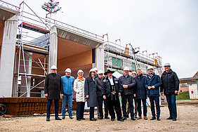 Gruppenfoto vom Richtfest mit Bezirkstagspräsident Peter Daniel Forster vor dem Rohbau