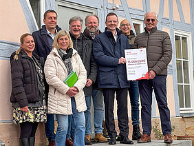 Gruppenfoto bei der Übergabe des Förderbescheids vor dem sanierten Gebäude.